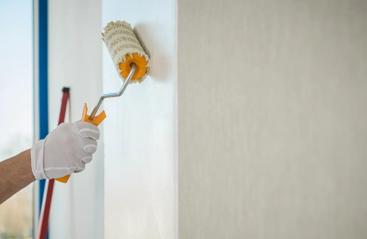 Ein Maler, der eine Wand mit einer Farbrolle streicht