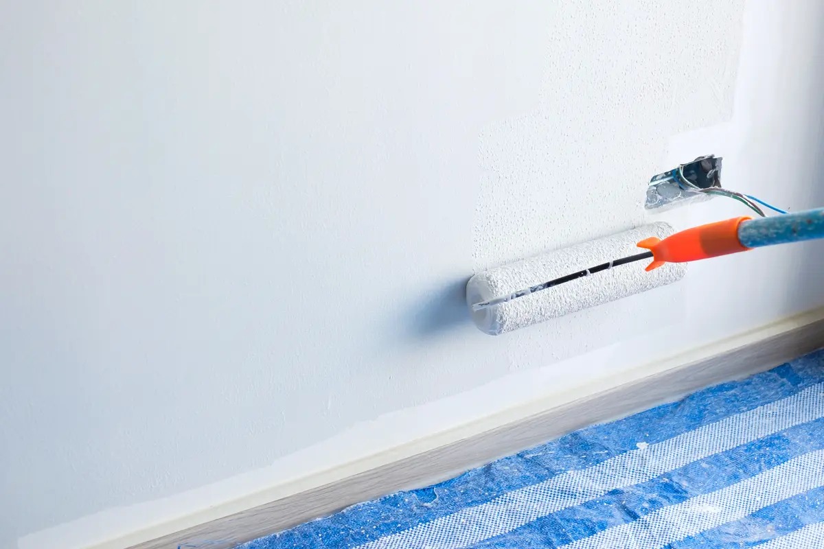 Malerarbeiten mit Rolle an Wand in einem Raum