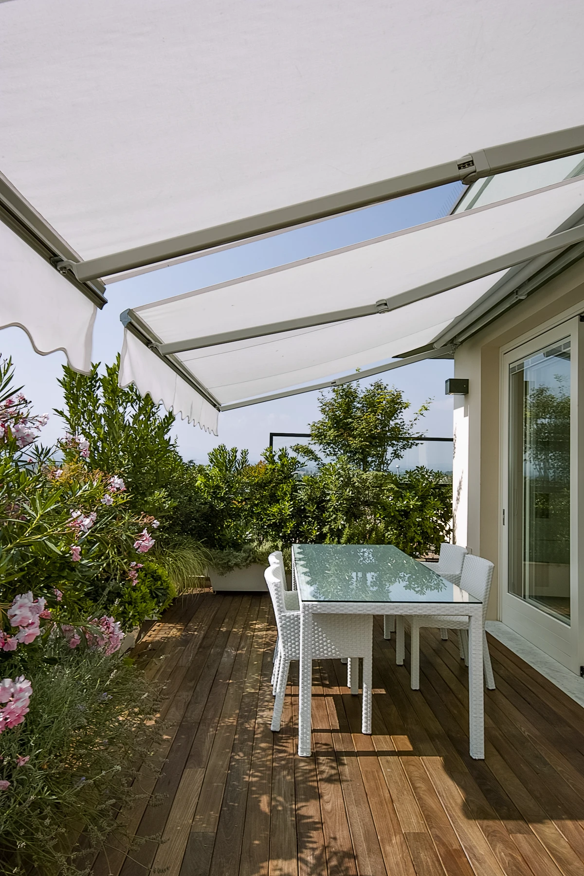 Terrassenüberdachung mit einem Tisch und Stühlen in einem begrünten Außenbereich