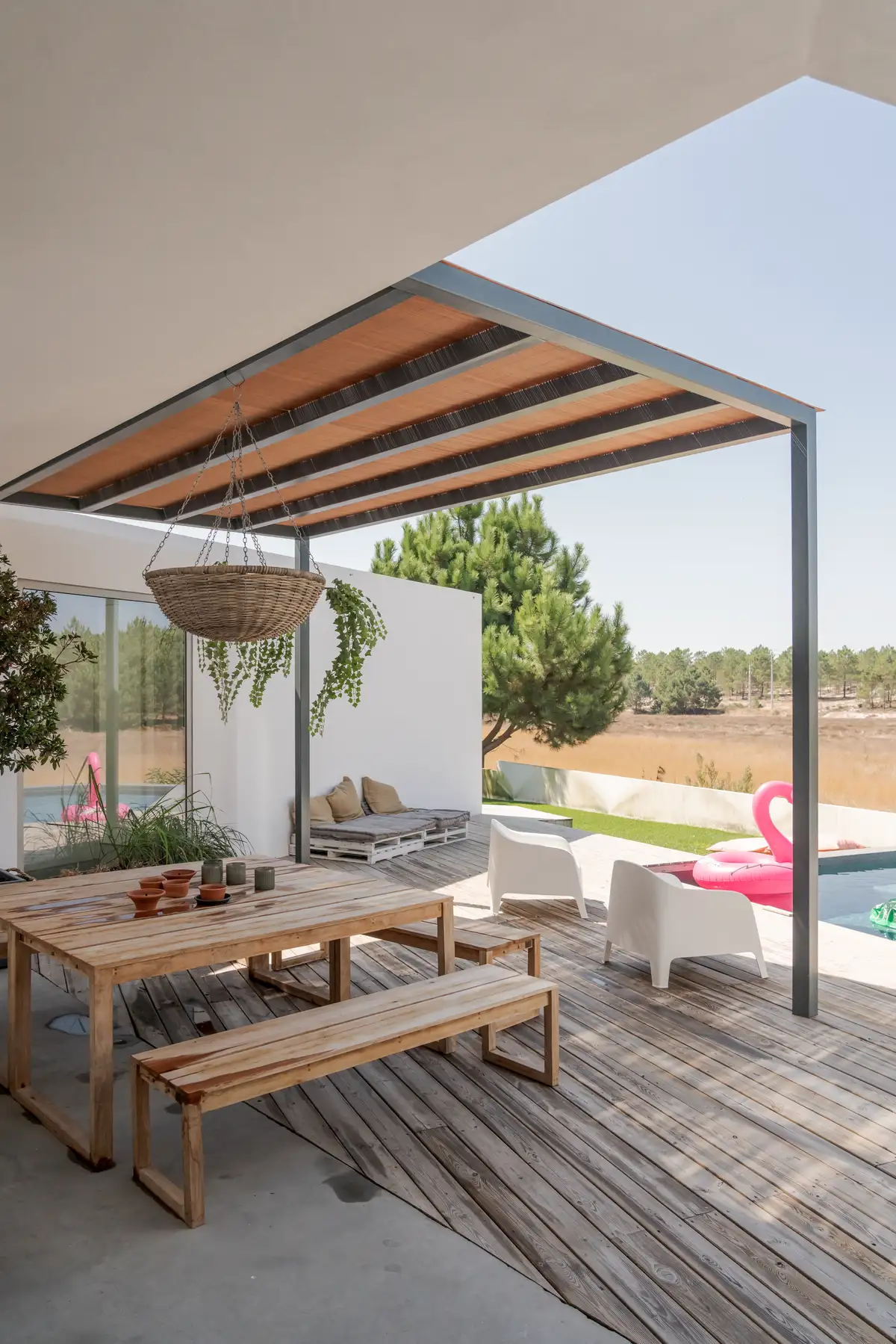 Terrasse mit Holztisch und Stühlen, überdacht mit modernen Streben