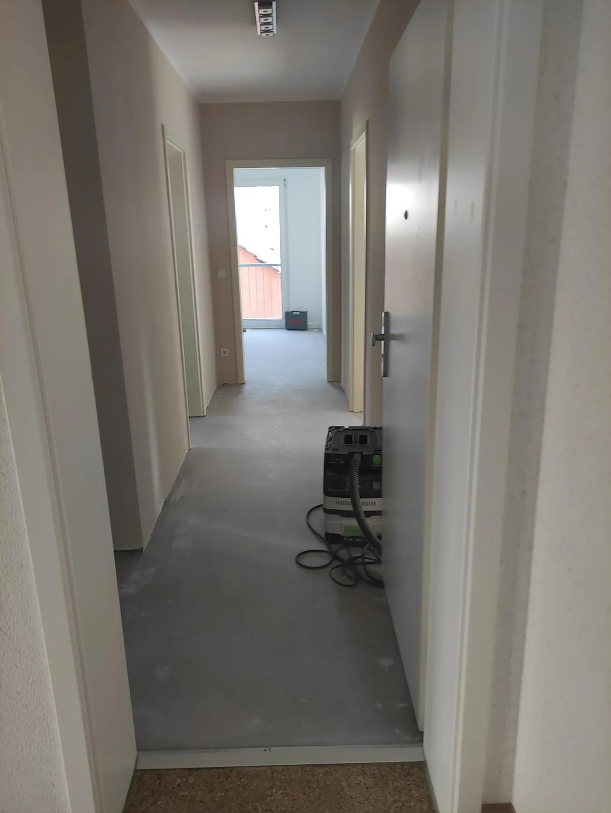 Sicht auf einen Flur mit offenen Türen und einem Baustellenstaubsauger