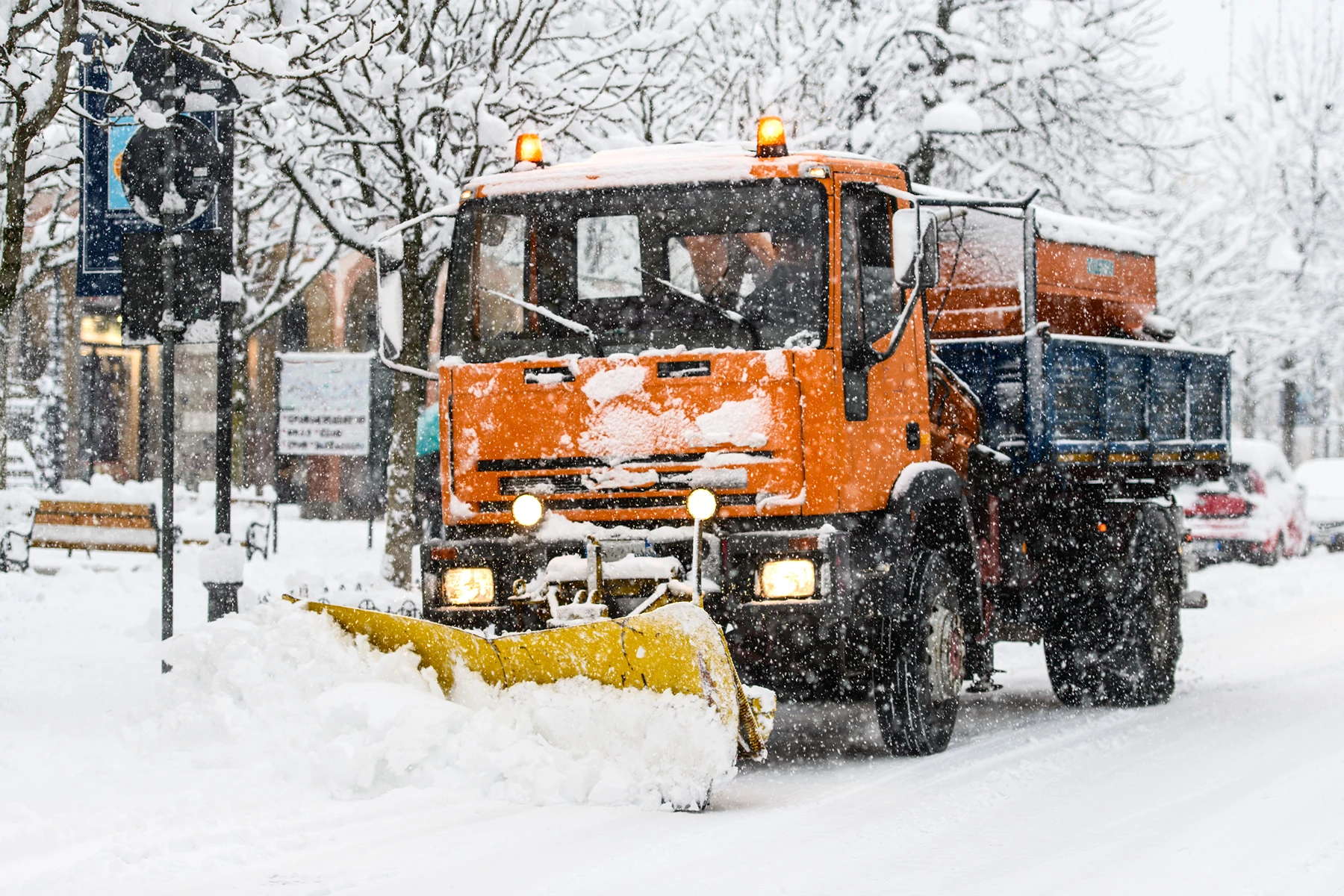 Schneeräumung mit einem orangefarbenen Räumfahrzeug in winterlicher Umgebung