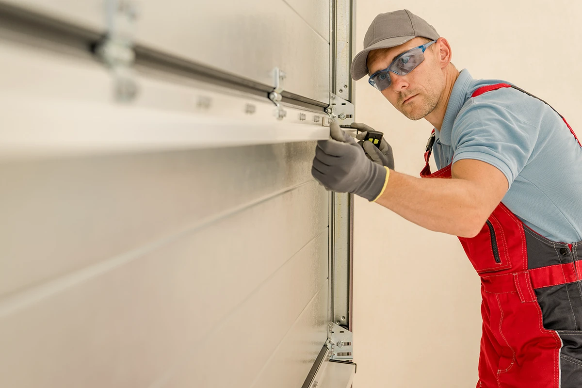 Ein Handwerker montiert ein Garagentor mit professionellem Werkzeug